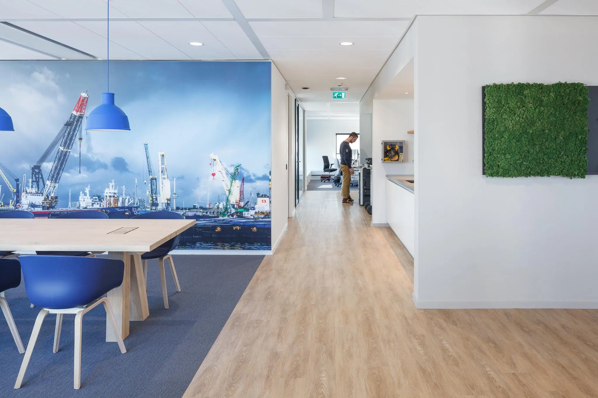 Moderne kantoorruimte in Rivium Quadrant met houten vloer, vergadertafel, havenmuurdecoratie en groene moswand.